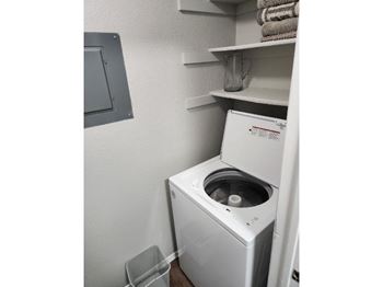 A white washing machine is installed in a small laundry room.